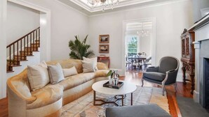 Un salon avec un canapé beige, une table basse, un lustre et une cheminée.