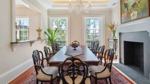 Une salle à manger élégante, avec une longue table, des chaises, un lustre et une cheminée.