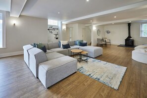 A spacious living room with a large sectional sofa, a round coffee table, and a fireplace. - Host & Stay | Stay House (Northallerton)