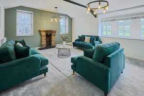 A living room with two green sofas, a round coffee table, and a fireplace.