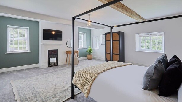 A bedroom with a four-poster bed, a fireplace, a large window, and a view of the outdoors.
