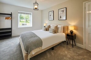 A bedroom with a bed, bedside lamps, a window, and a hanging rack. - Host & Stay | Stay House (Northallerton)