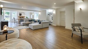 A spacious living room with a large sectional sofa, a round coffee table, and a fireplace.
