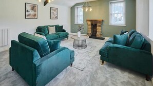 Un salon avec des canapés de couleur turquoise, une table basse ronde et une cheminée.
