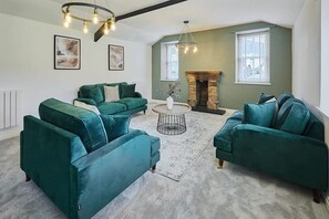 A living room with teal sofas, a round coffee table, and a fireplace. - Host & Stay | Stay House (Northallerton)