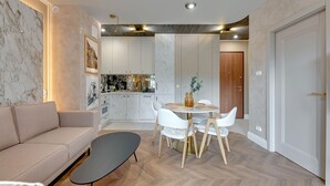 A modern living room with a sofa, a dining table with chairs, and a kitchen in the background. - RentPlanet - Sienna Grobla (Gdansk)