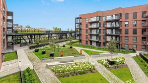 A modern apartment complex with multiple balconies, a pedestrian bridge, and landscaped gardens. - RentPlanet - Sienna Grobla (Gdansk)