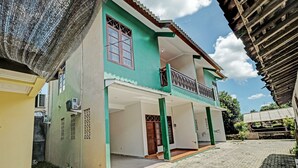 Un edificio de dos pisos con un balcón, un porche cubierto y un patio empedrado.