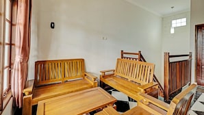 Habitación con muebles de madera, incluyendo bancos y mesas, una escalera con barandilla de madera, y una ventana con cortinas.