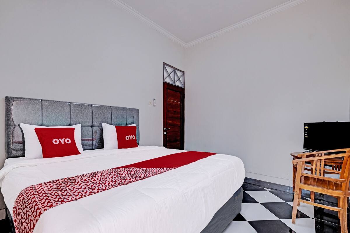 Ein Hotelzimmer mit einem Bett, einem Fernseher und einem Sessel.