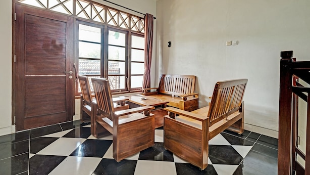 Una habitación con piso a cuadros, muebles de madera y un ventanal con cortinas.