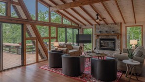 Amplia sala de estar con chimenea, ventanas grandes y una terraza.