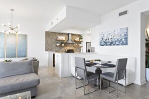 Eine moderne Küche mit weißen Schränken, einer Rückwand aus Holzverkleidung im Fischgrätmuster und einer zentralen Kochinsel mit Sitzgelegenheit.