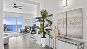 Ein modernes Wohnzimmer mit großem Fenster, Deckenventilator, Sofa, Couchtisch und einer Topfpflanze.