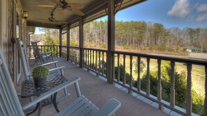 A covered porch with a view of a forested area, featuring a ceiling fan, outdoor seating, and a railing. - Large Cabin Near the town of Blue Ridge! (Blue Ridge)