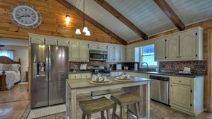 A spacious kitchen with wooden beams, a stainless steel refrigerator, a microwave, and a dishwasher. - Large Cabin Near the town of Blue Ridge! (Blue Ridge)