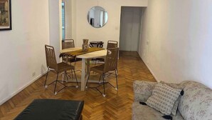 Un coin repas avec une table ronde, quatre chaises et un miroir au mur.