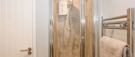 Un baño moderno con ducha de vidrio, una puerta blanca y un perchero para toallas.