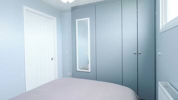 A bedroom with a bed, a wardrobe, a mirror, and a radiator.
