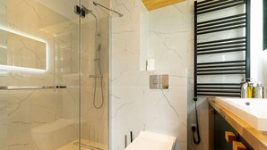 A modern bathroom with a glass-enclosed shower, a toilet, and a sink with a wooden countertop. - RentPlanet - Kras Resort (Szklarska Poreba)
