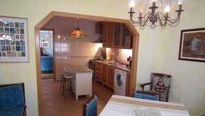 Ein Essbereich mit Tisch für zwei Personen, eine Küche im Hintergrund und eine Chandelier.