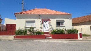 Ein zweistöckiges Haus mit rotem Ziegeldach, weißem Anstrich und einem roten Tor.