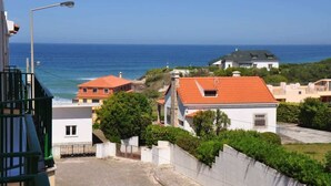 Ein Küstenwohngebiet mit Häusern, freiem Blick auf das Meer und einer Straße mit einer Straßenlaterne.