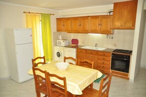 Una cocina compacta con armarios de madera, un refrigerador, un microondas, una lavadora y una estufa.