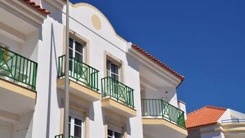 Un bâtiment blanc avec des balcons verts et un toit recouvert de tuiles rouges.