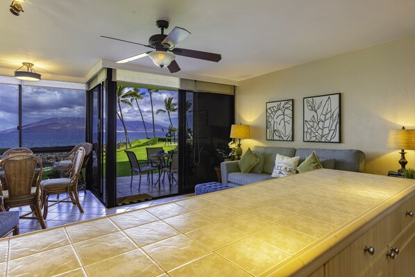 Habitación con un ventanal grande que ofrece una vista panorámica, ventilador de techo y zona de comedor con sillas y mesa.
