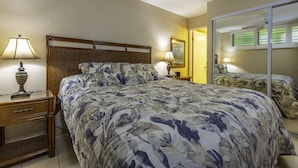 A hotel room with a large bed, a nightstand, a lamp, a mirror, and a ceiling fan.