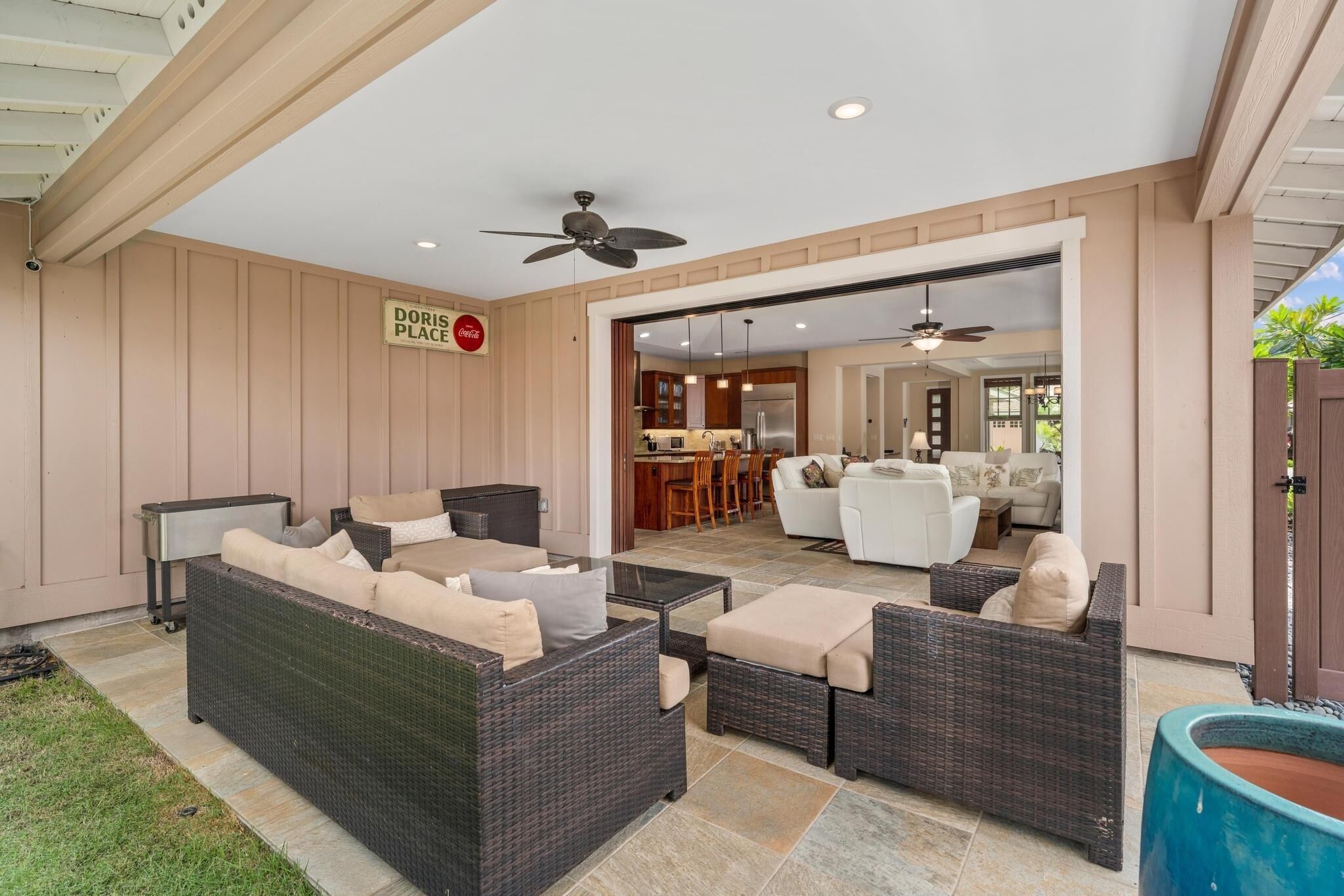 A covered patio area with wicker furniture, a dining area, and a kitchen visible through an open doorway.