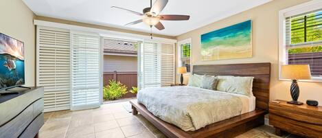 A bedroom with a bed, a ceiling fan, a TV, and a window with blinds.