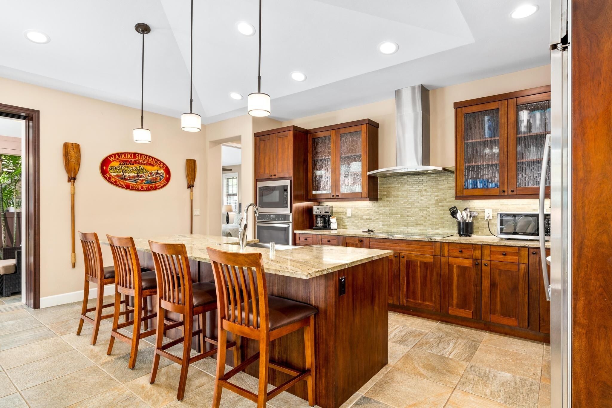 A modern kitchen with wooden cabinets, a large island with bar stools, and pendant lighting.