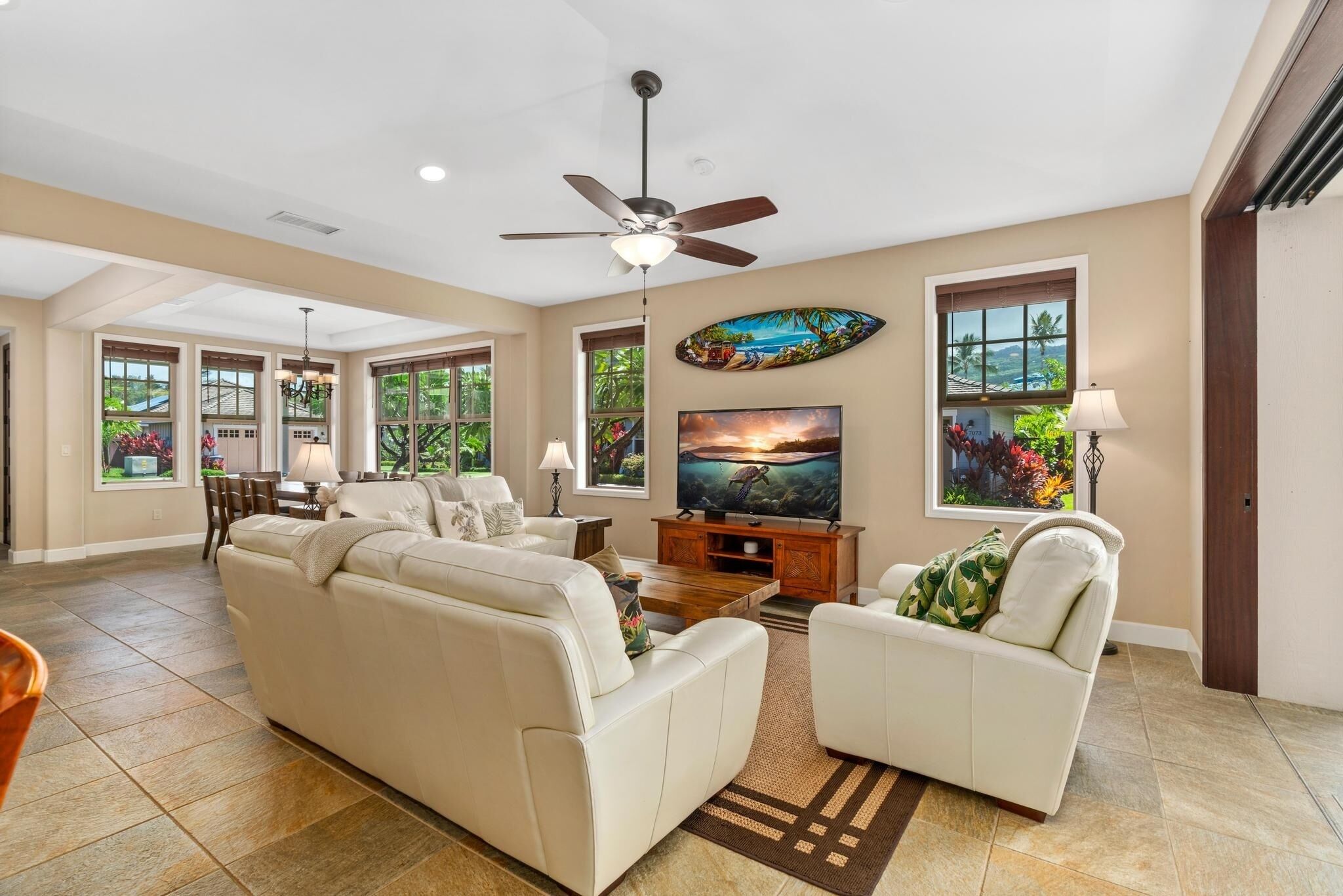 A spacious living room with a large sofa, a television, and a ceiling fan.