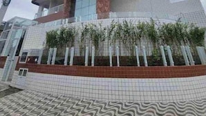 A multi-story hotel with a curved facade, large windows, and a tiled ground floor. - Excelente Apto com piscina em Praia Grande (Praia Grande)
