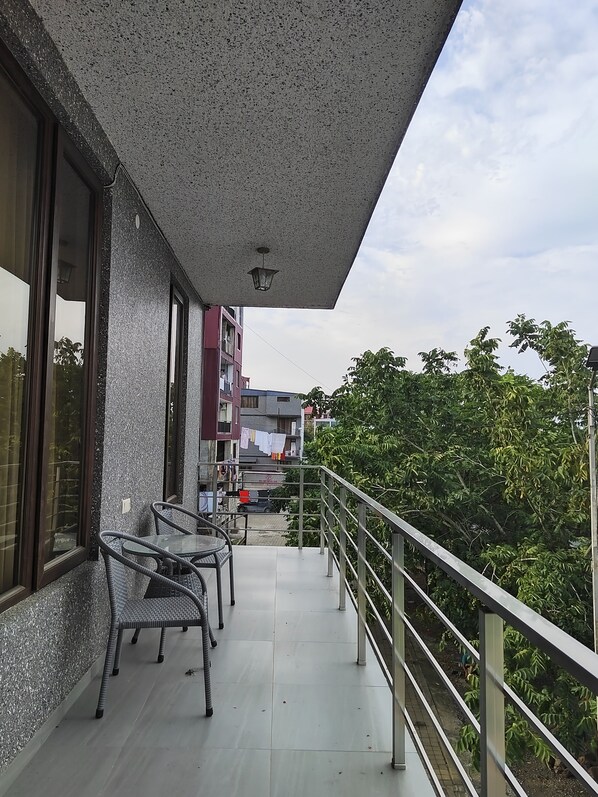 A balcony with a metal railing, a table, and two chairs.