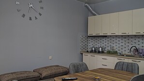 Ein modernes Wohnzimmer mit einem Holzesstisch, einer grauen Couch und einer Wanduhr.
