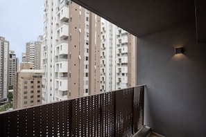 A high-rise building with multiple balconies, a modern railing design, and a small wall-mounted light fixture.