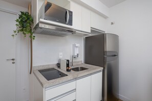 Cozinha moderna com micro-ondas embutido, geladeira de aço inoxidável e bancada de granito.