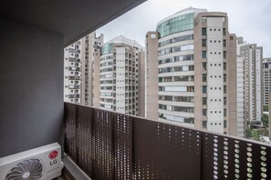 A balcony with a view of high-rise buildings, an air conditioning unit, and a perforated metal railing. - Walk Moema (São Paulo)