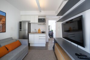 A modern kitchen with a central island, built-in appliances, and a large flat-screen TV. - Walk Moema (São Paulo)