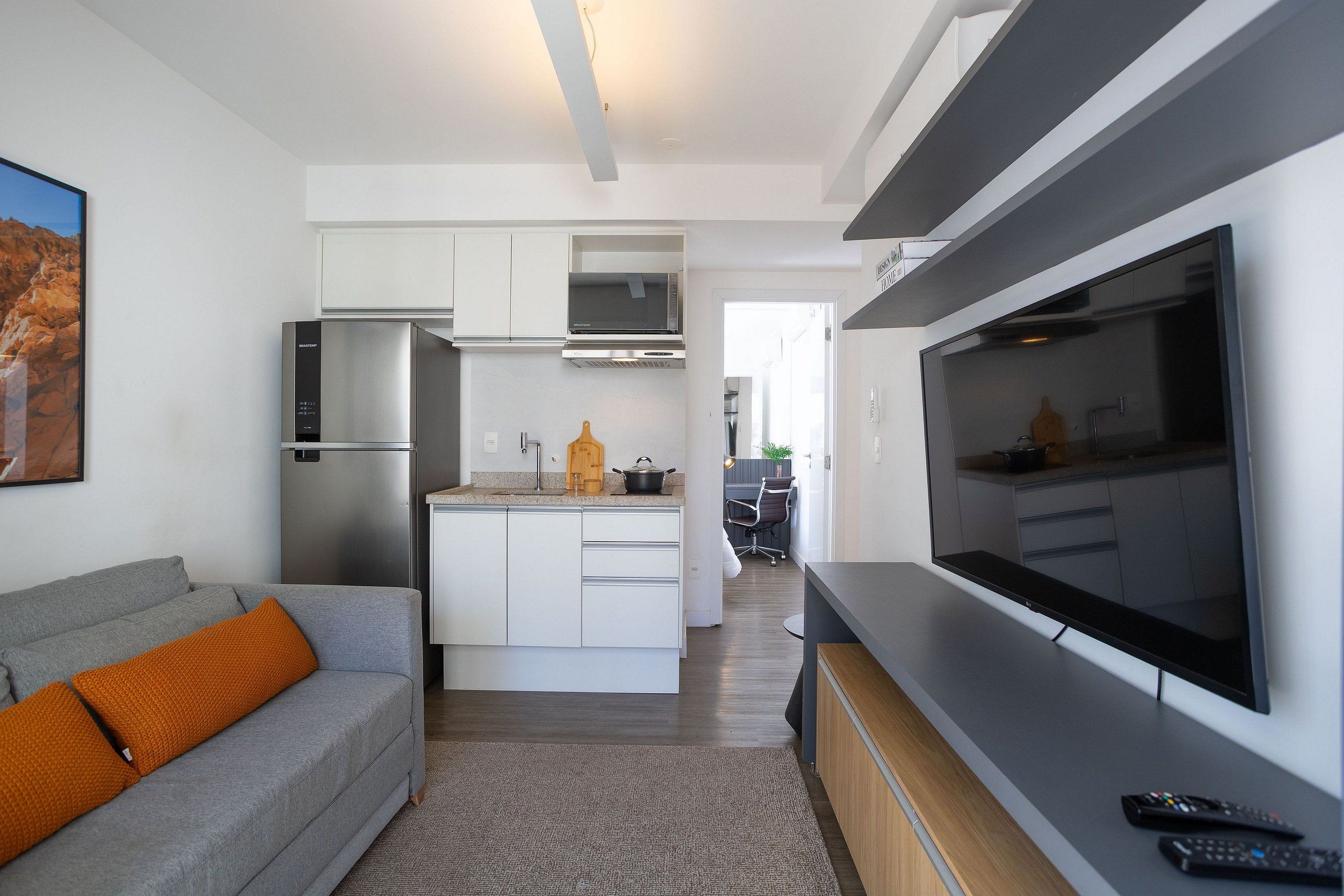 A modern kitchen with a central island, built-in appliances, and a large flat-screen TV.