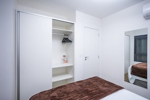 A bedroom with a bed, a wardrobe, and a mirror. - Walk Moema (São Paulo)