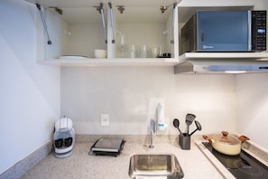 A compact kitchen with a microwave, coffee maker, and a small sink.