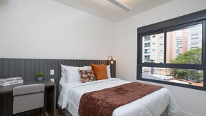 Un dormitorio moderno con una cama, un escritorio y una ventana.