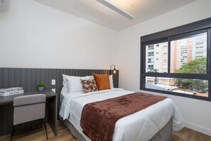 A modern bedroom with a bed, a desk, and a window.