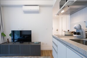 A modern kitchen with a built-in stove, a microwave, and a coffee machine. - Walk Moema (São Paulo)