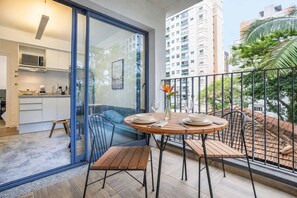 Een balkon met een eettafel, stoelen en uitzicht op de stad.
