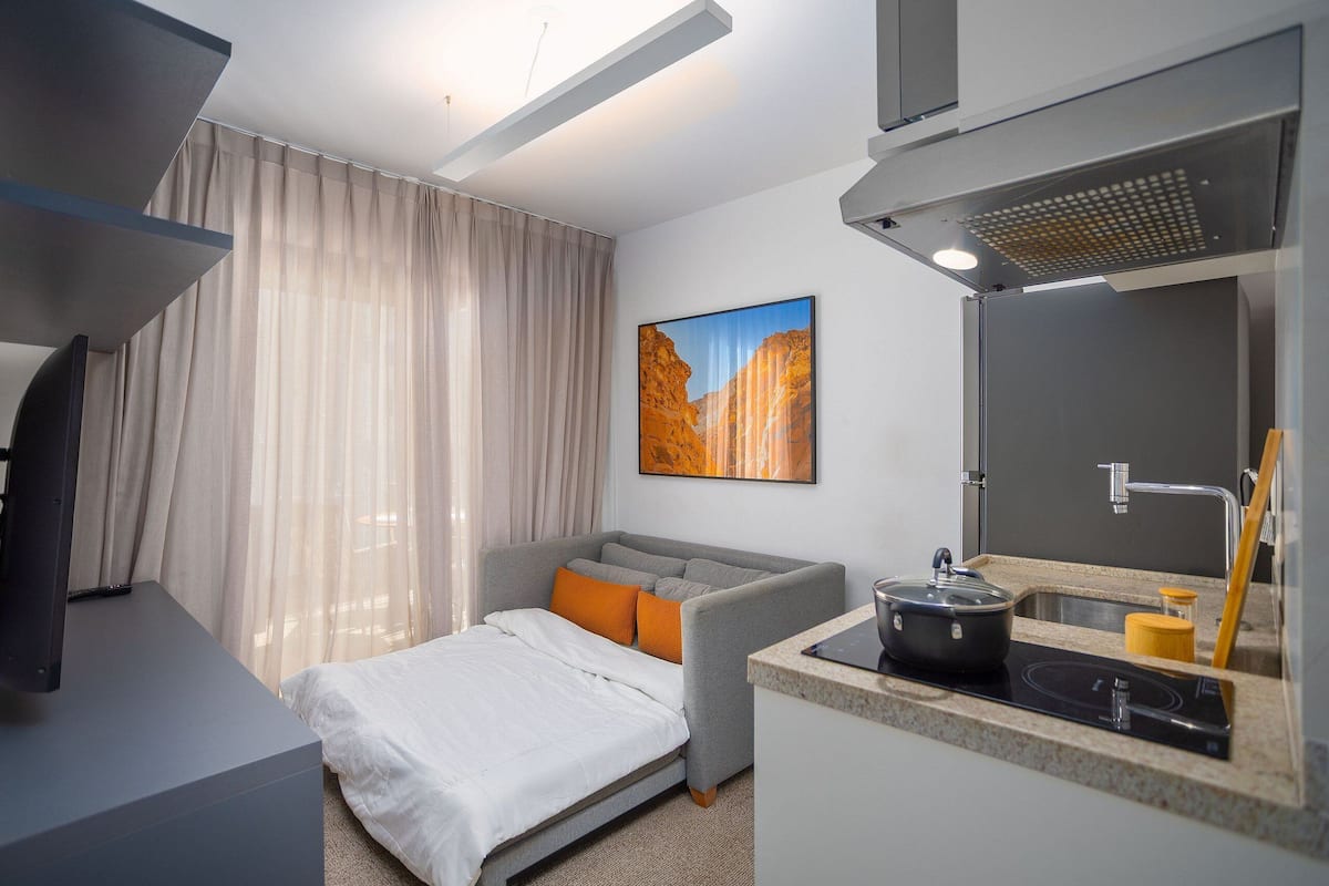 Ein modernes Hotelzimmer mit Bett, einer Sitzecke, einer kleinen Küchenzeile und einem Bild an der Wand.